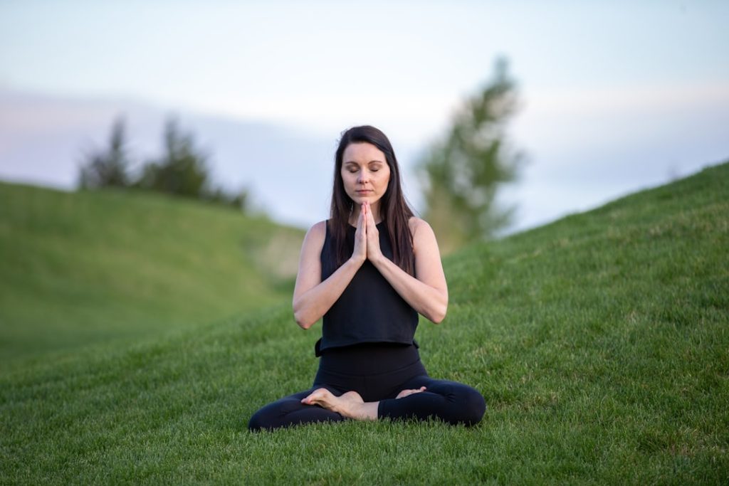 woman-in-black-tank-top-and-black-pants-sitting-on-green-grass-field-during-daytime-ron57cbgymo